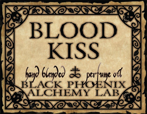 Label for 'Blood Kiss' hand blended perfume oil by Black Phoenix Alchemy Lab with decorative border.