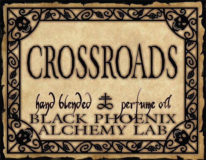 Label for 'Crossroads' hand blended perfume oil by Black Phoenix Alchemy Lab with decorative border.