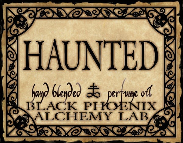 Label for 'Haunted' hand blended perfume oil by Black Phoenix Alchemy Lab with decorative border.