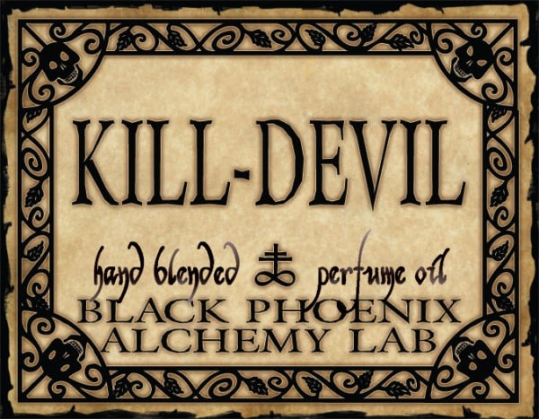 Label for 'Kill Devil' hand blended perfume oil by Black Phoenix Alchemy Lab with decorative border.