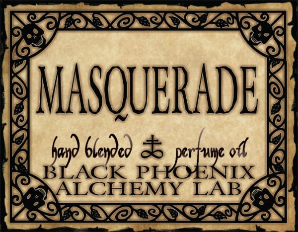 Label for 'Masquerade' hand blended perfume oil by Black Phoenix Alchemy Lab with decorative border.