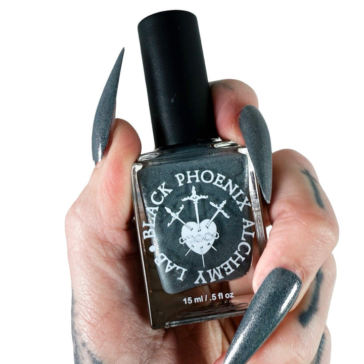Hand holding a bottle of Black Phoenix Alchemy Lab nail polish with stiletto nails.