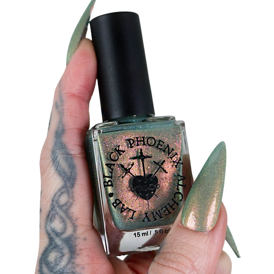 Hand holding a bottle of Black Phoenix Alchemy Group nail polish with a black cap.