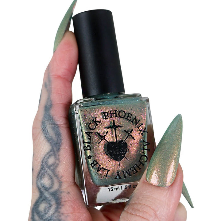 Hand holding a bottle of Black Phoenix Alchemy Group nail polish with a black cap.