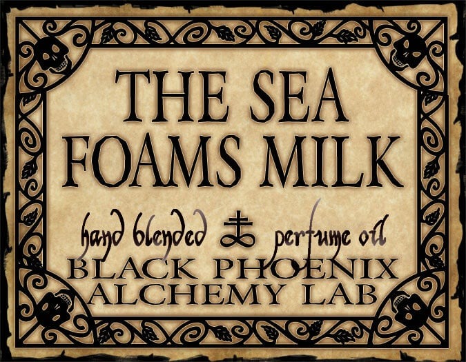 Label for 'The Sea Foams Milk' hand blended perfume oil by Black Phoenix Alchemy Lab with decorative border.